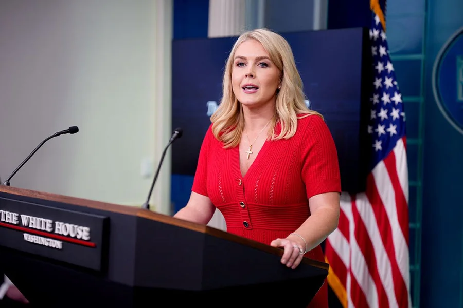 Porta-voz da Casa Branca, Karoline Leavitt, falando em púlpito com a bandeira dos Estados Unidos ao fundo.