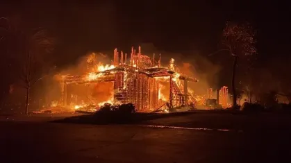 Fumaça densa e chamas consumindo armazém logístico em Ontario, Califórnia, durante a noite.