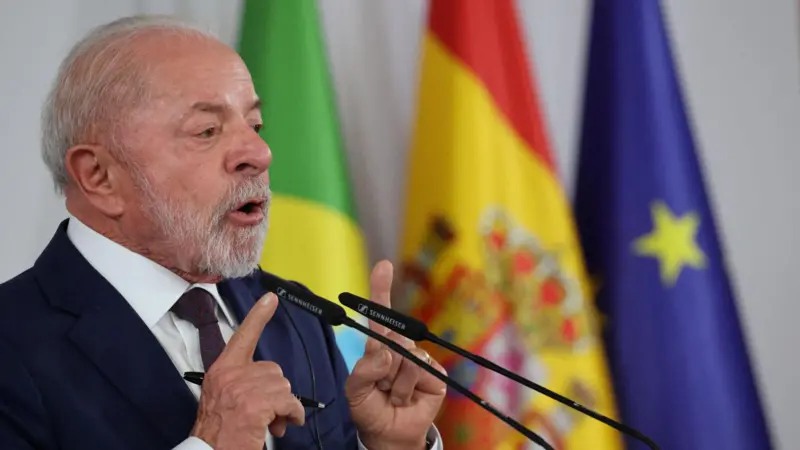 Presidente Lula discursando em pódio na Alemanha com bandeiras ao fundo.