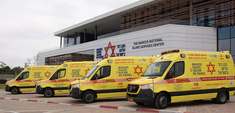 Fachada de um centro médico em Israel com movimentação de ambulâncias.