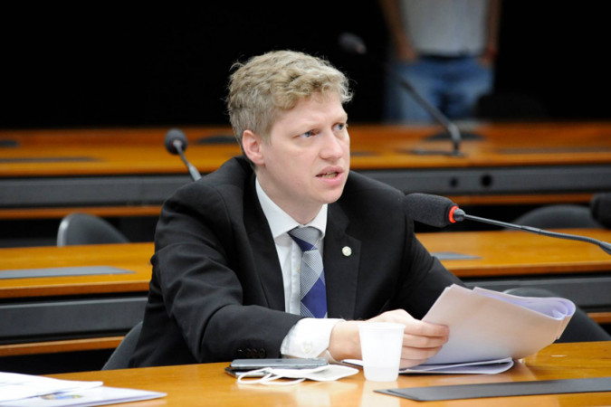 : Deputado Marcel van Hattem gesticula indignado durante discussão com assessor militar nos corredores do Congresso Nacional.