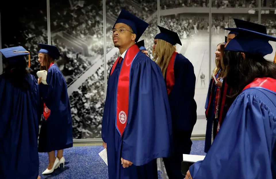Chris Young sorrindo com a bata de formatura azul da Southern Methodist University (SMU).
